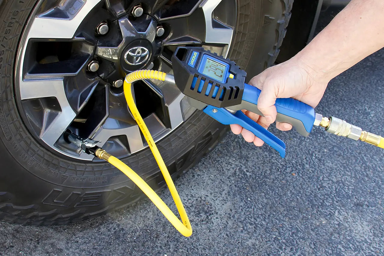 Person using a digital tire pressure gauge on a car tire.