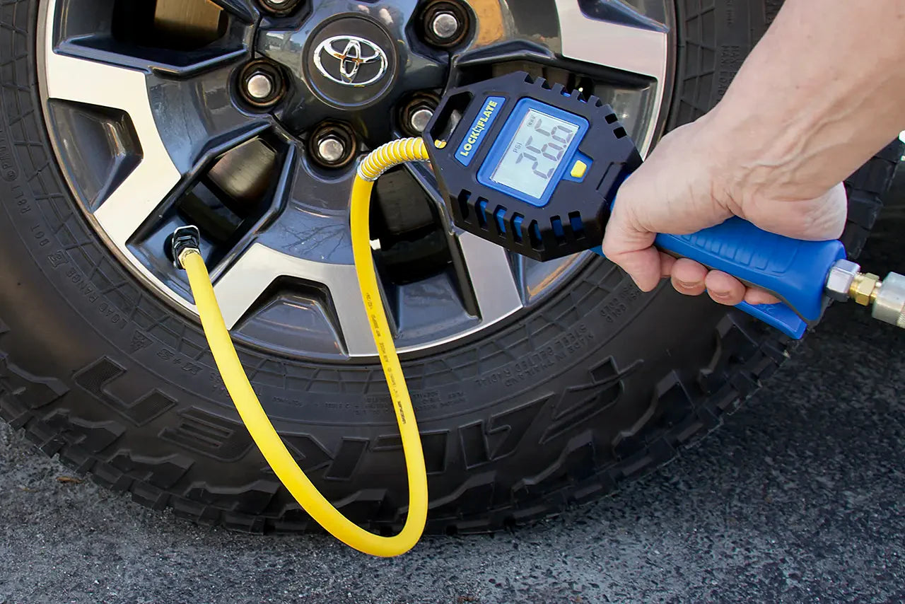 Digital tire pressure gauge being used on a car tire