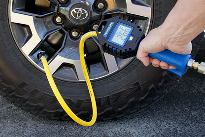 Digital tire pressure gauge being used on a car tire
